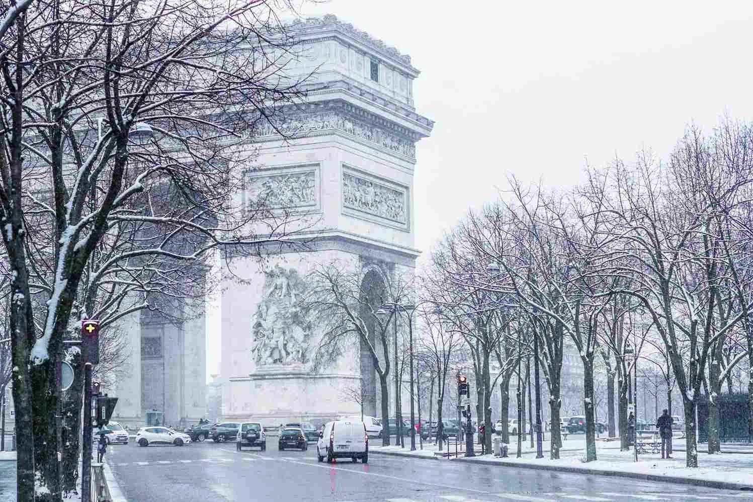 منظرهای برفی از طاق پیروزی در پاریس با درختان پوشیده از برف و خیابانهای آرام در فصل زمستان.